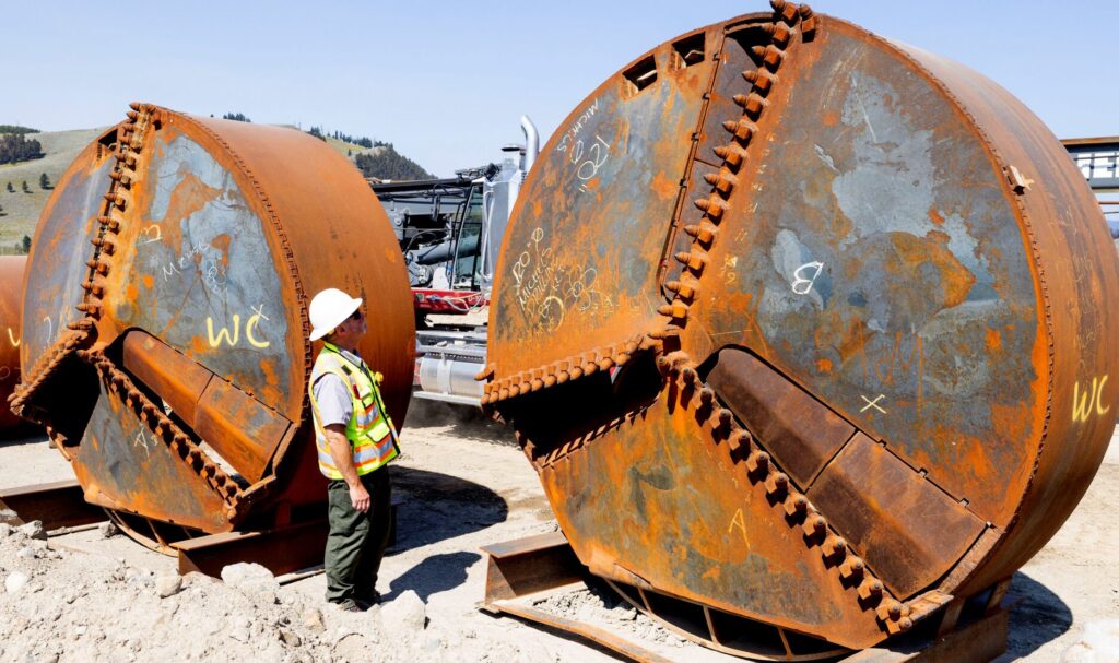 Dan Rhodes, a Park Service landscape architect, examines the 10-foot diameter pier drill bits used in the construction of a new Yellowstone River bridge in 2023.
